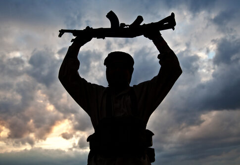 Silhouette of a person holding a rifle against a cloudy sky
