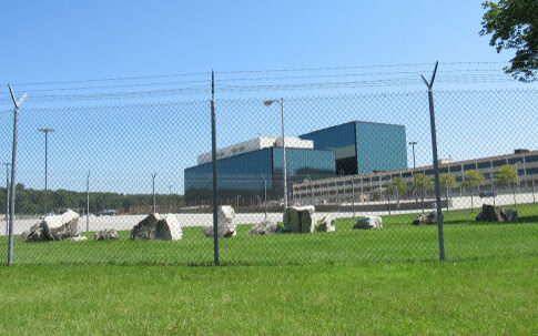 Chain-link fence in front of a large modern office complex