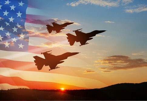 Three fighter jets fly in formation at sunset with a translucent U.S. flag overlay