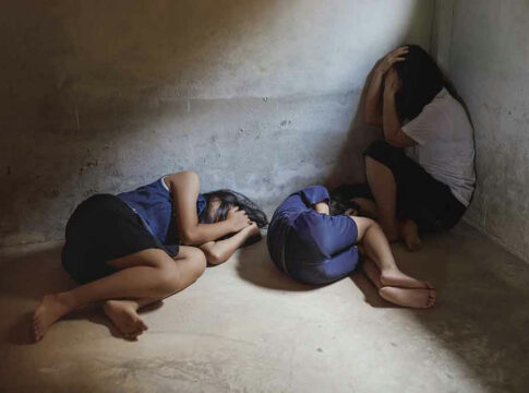 Three people huddled in a dimly lit corner.