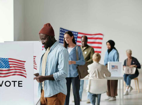 People voting in a polling station with American flags.