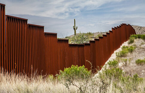 rust-colored border fence in a desert landscape