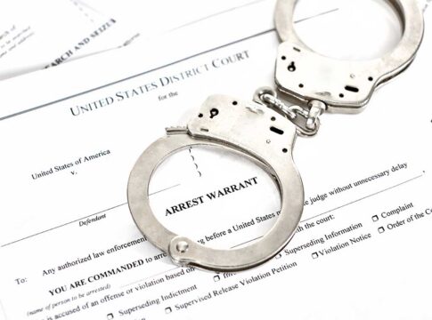 Handcuffs on an arrest warrant document