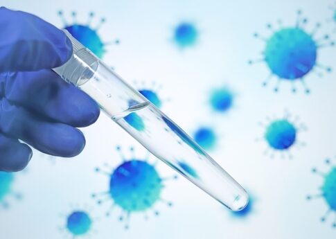 A gloved hand holding a test tube with a clear liquid against a blue virus background