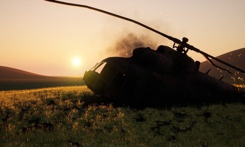 Abandoned military helicopter in a grassy field during sunset