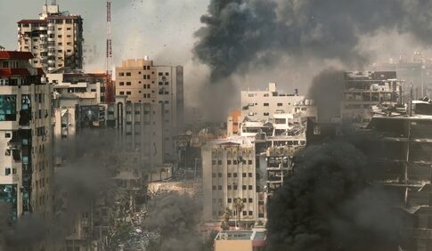A cityscape showing damaged buildings and thick smoke rising from the ground