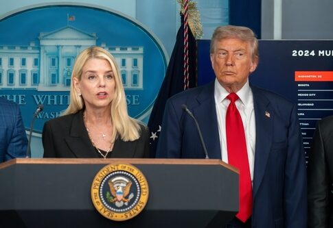Two government officials at a press conference in front of the White House backdrop