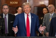 Wine Wars: Inside the MAGA Power Struggle…. A public figure speaking at a press conference with a group of people in the background