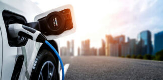 Electric car charging with city skyline background.