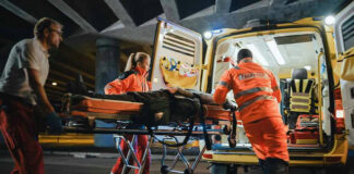 Paramedics loading patient into ambulance at night.
