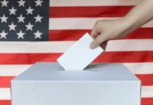 Trump Axes Election Umpires Weeks Before Votes Hand casting ballot into box before U.S. flag