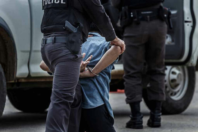 659470525 Police officer arresting and handcuffing a person.