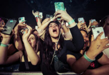 Supergirl Meltdown: “Woke Flop” Concert crowd cheering and taking photos with phones.