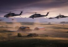 Military helicopters fly low over a rural farm at sunset